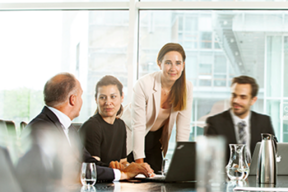 Colleges sitting around a table looking at information on a laptop