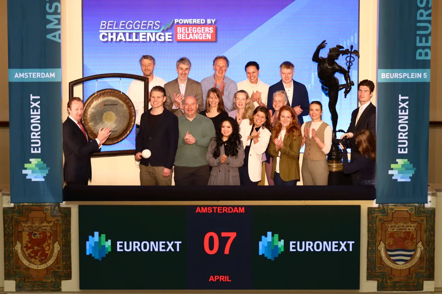 A group from Beleggers Belangen stands on the trading floor at Euronext Amsterdam as the winner of the preliminary round sounds the gong to mark the start of the investment competition, accompanied by Euronext representatives.