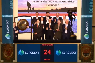 Representatives from XtraAdvice and Lymph & Co stand together as the ceremonial gong is rung at Beursplein 5, marking the start of the 10th Hollandse 100 and honouring the memory of Rudolf van Schaik.